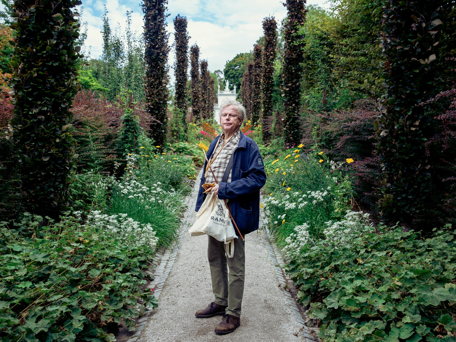 Petter Olsen står på en gangsti mellom ulike planter. Foto.