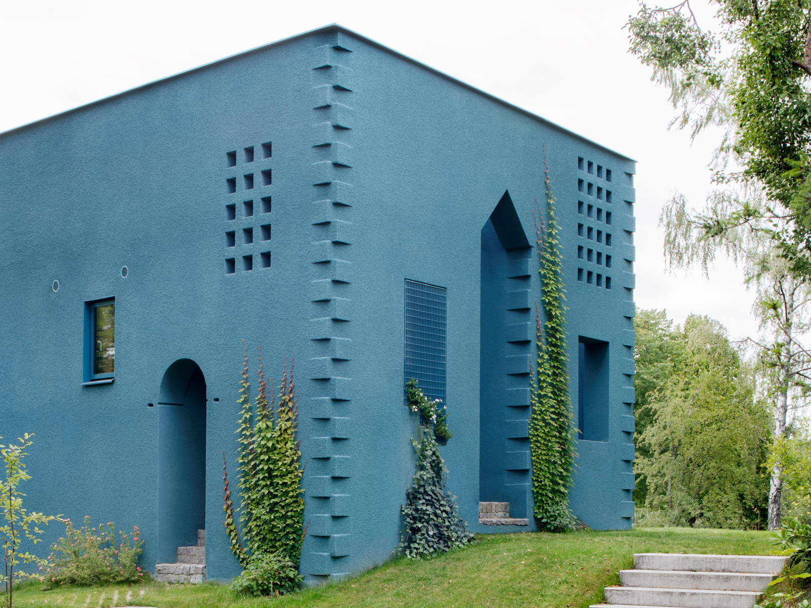 Foto av et blått hus i en grønn hage.