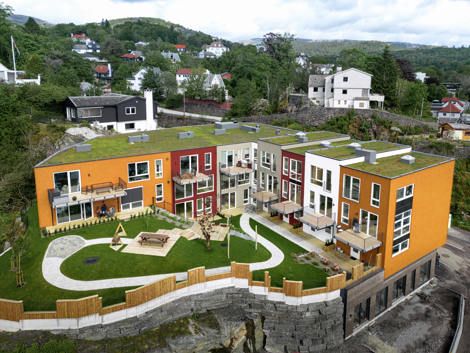 Oversiktsbilde av fargerikt boligkompleks med grønn bakgård. Foto. 