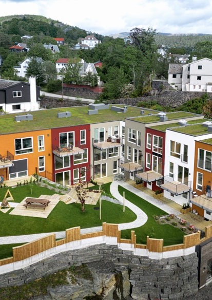 Oversiktsbilde av fargerikt boligkompleks med grønn bakgård. Foto. 