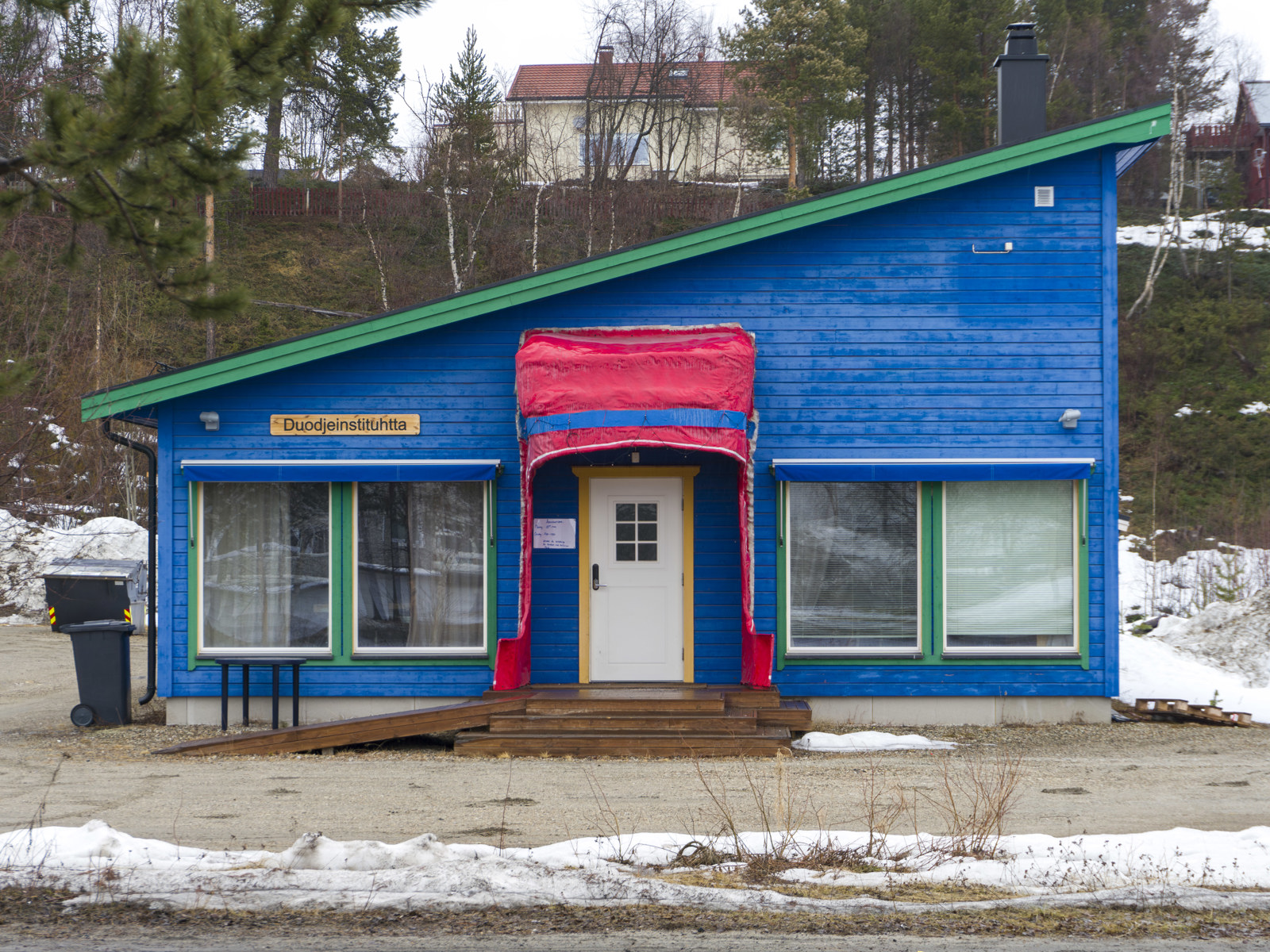 Foto av blått hus med inngangsparti som ligner en samekvinne sin lue. 