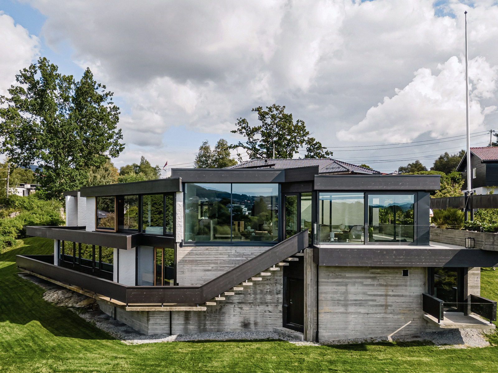 Fasade foto av villa i ulike vinkler i betong og mørkt treverk, og store glassflater.