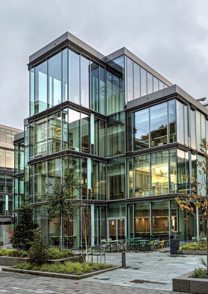 Foto av fasaden på Glasblokkene, vegetasjon og hardt underlag på plassen fremfor.