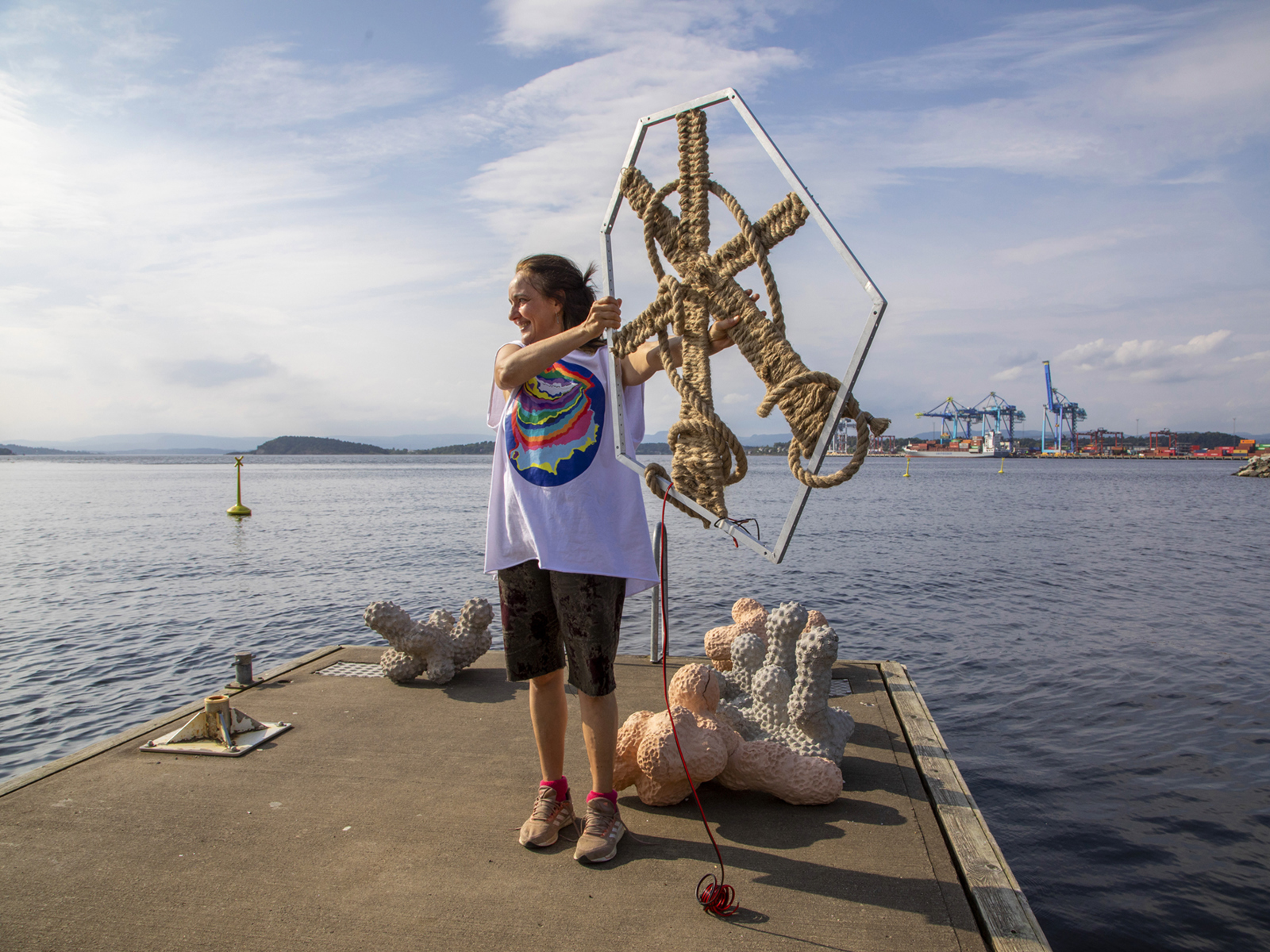 Foto av Elin T. Sørensen som holder oppe en gjenstand med tau, på en brygge.