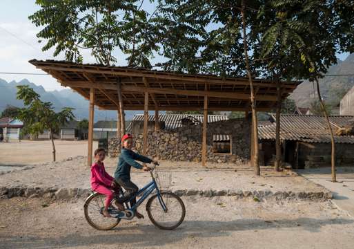 2 barn på en sykkel på landsbygda i Vietnam. Foto.
