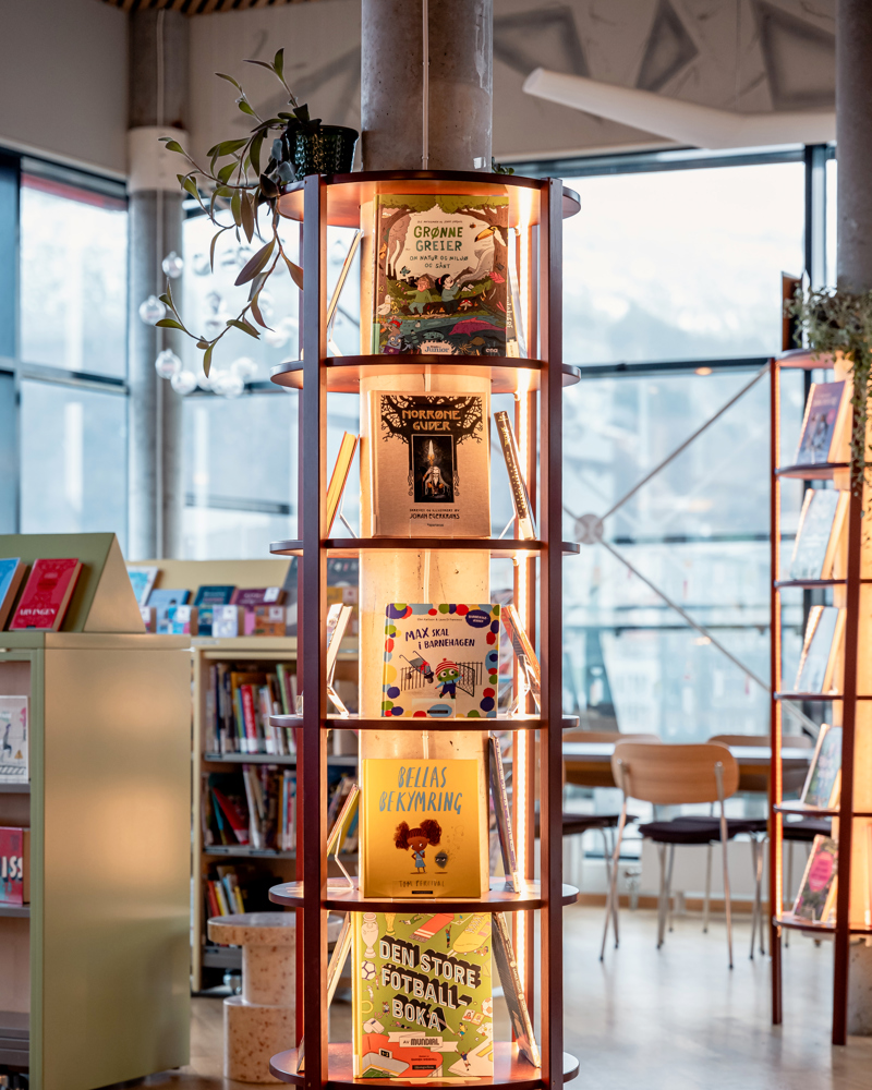 Interiør foto av hylle i bibliotek som viser frem bøker rundt en betong søyle.