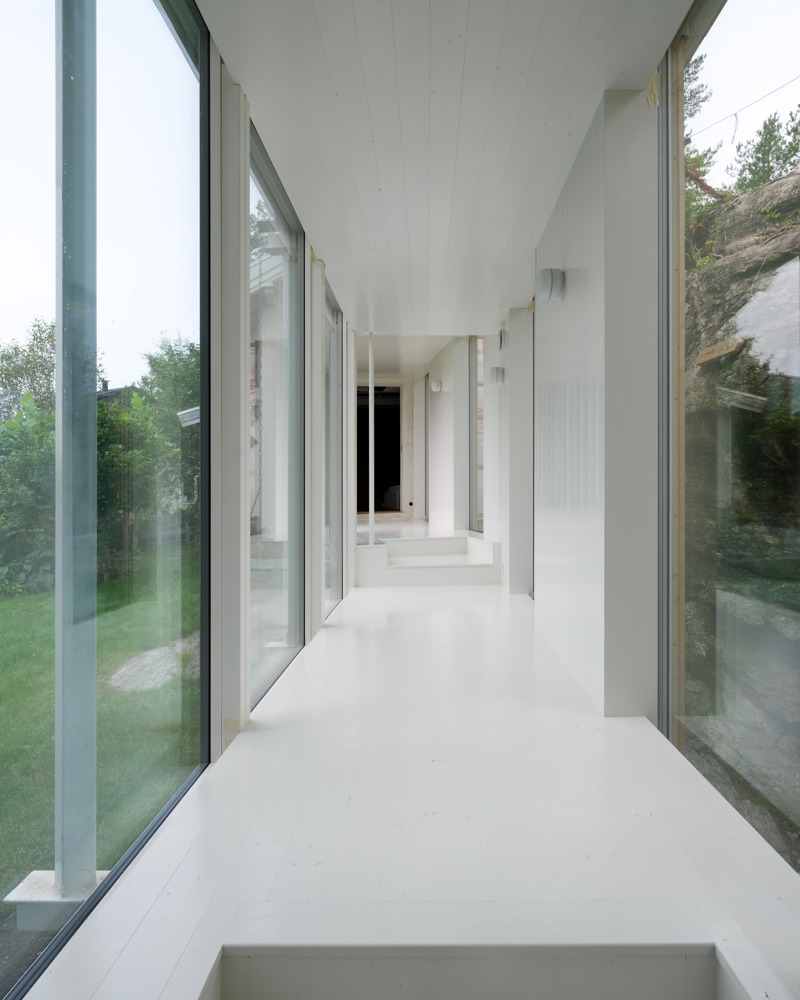 Interiør foto av gang med glassvegg på en side og hvite vegger på andre siden.