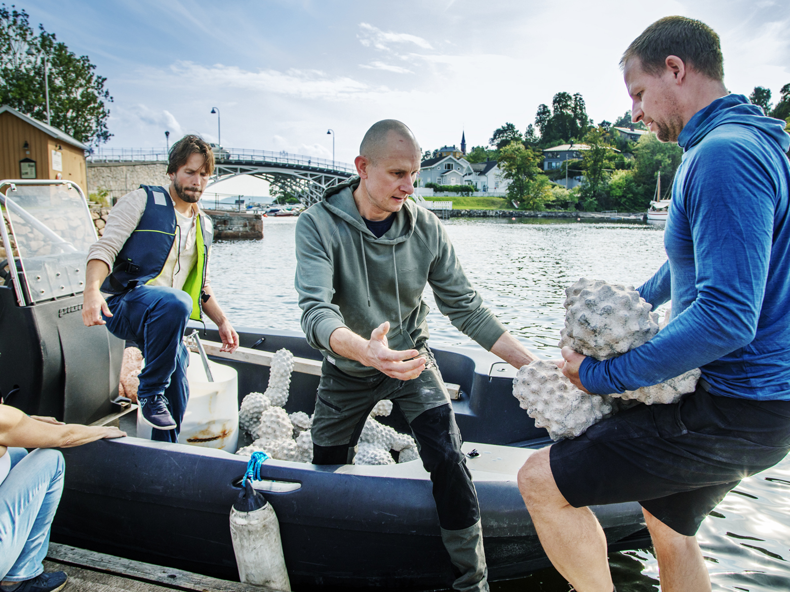Foto av noen menn som lemper noen klumpete gjenstander opp i en liten båt.