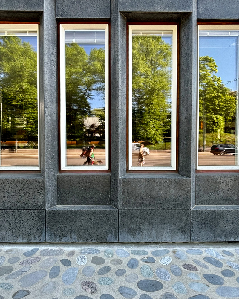 Foto av fasaden på den amerikanske ambassaden i Oslo, refleksjon av trær i vindu.